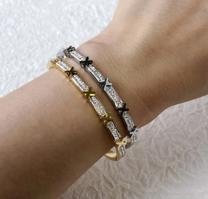 Close-up of gold and silver X-letter stainless steel bracelets with pavé crystal detail