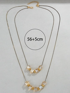 Detalle de collar dorado de doble capa con perlas de cristal champán y etiqueta de talla