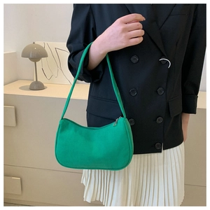 Detail of green corduroy baguette bag worn by model in a minimalist indoor setting
