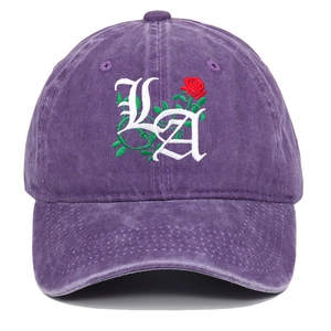 Detailed view of LA gothic letters and red rose embroidery on a purple washed cotton cap