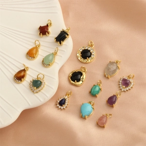 Mix of colorful gemstone pendants in gold plating featuring heart and drop shapes on a tray