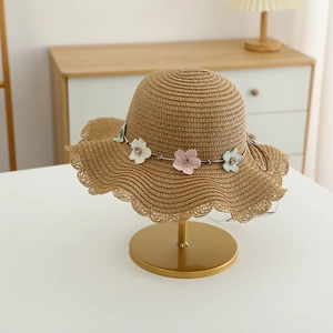 Détail du chapeau de paille fille avec broderie florale et bords ondulés ajourés