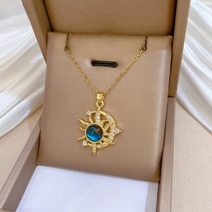 Detail of gold star and moon pendant with shimmering blue stone and pave crystals