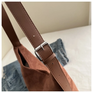 Detail of adjustable leather strap and silver buckle on a vintage brown velvet tote bag