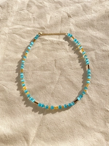 Flat lay of cat-eye stone beads necklace with golden clasp on beige linen fabric