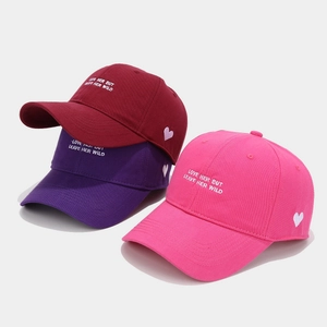 Close-up of heart embroidery and script text on colorful cotton twill baseball caps