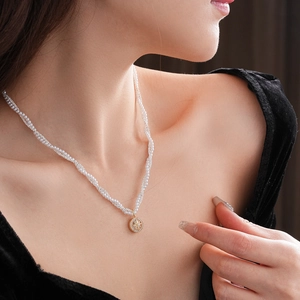 Close-up of double-layer pearl necklace with a gold star pendant on a model
