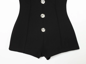 Detail of three large crystal buttons on a black slim fit jumpsuit with premium fabric