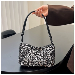 Detail of sequined baguette bag showing silver and black sequins with knot strap detail