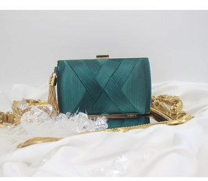 Detail of emerald green satin evening clutch with gold metal fringe tassel and clasp