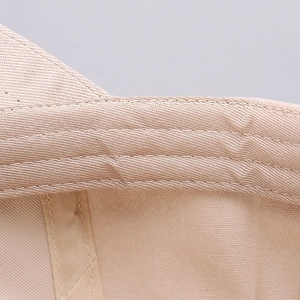 Close-up of the fine double-stitched seams and twill texture on the beige baseball cap