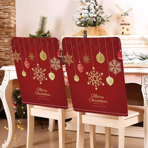 Detail of red Christmas chair covers with gold snowflake patterns on white wooden chairs