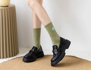 Detail of green mid-calf socks with planet embroidery paired with black loafers