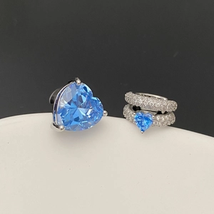 Détail de boucles d'oreilles cœur argentées avec cristaux bleus et accents de zircon
