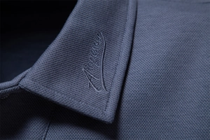 Macro detail of navy blue pique cotton polo collar with delicate art embroidery