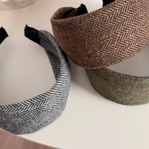 Detail view of knitted wide headbands in brown, gray and green herringbone tweed fabric