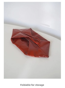 Close-up of the foldable red-brown soft leather bag showing its flexible storage design