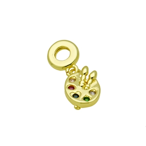 Macro shot of gold palette pendant with colorful gems and two brushes on white background