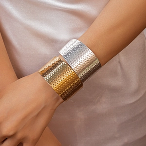 Detail of wide hammered texture cuff bracelets in gold and silver finish on wrist