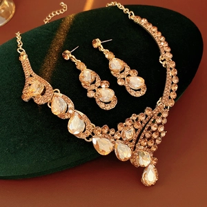 Détail de parure bijoux vintage avec strass champagne sur un support en velours vert