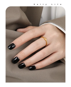 Detailed view of a gold sunflower ring on model finger with black nail polish