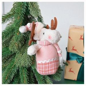 Close-up of a pink reindeer plush ornament with scarf hanging on a Christmas tree branch