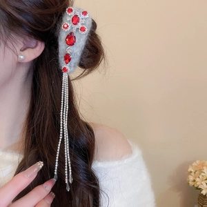 Detail of grey velvet hair clip featuring red gemstones and long silver rhinestone tassels