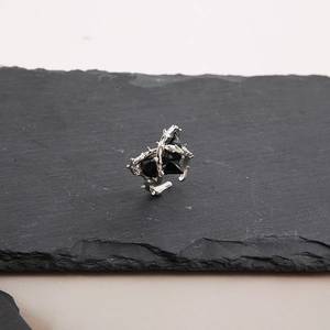 Macro shot of silver gothic thorn rings with black stones on a dark stone plate