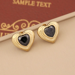 Macro shot of vintage heart studs with gold base and black gemstone on a gift box