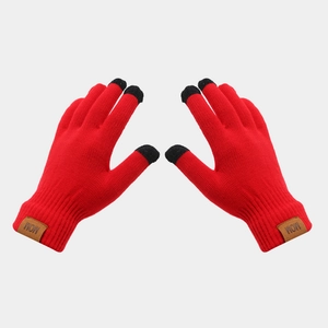 Detail of red knit gloves with black touchscreen fingertips and brown leather MOM tag