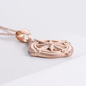 Close-up of rose gold compass pendant with textured sandblasted relief detail