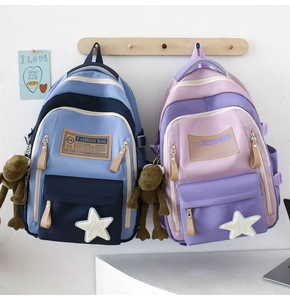 Close-up of stylish high school backpacks with star patches and plush frog pendants