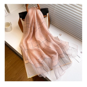 Detail view of pink striped silk wool scarf draped over a classic handbag by a window