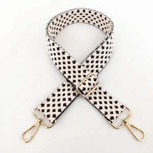 Detail of adjustable black and white houndstooth woven strap with gold metal swivel hooks