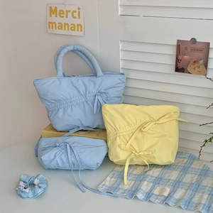 Pleated drawstring handbags in light blue and yellow colors on a cozy home desk