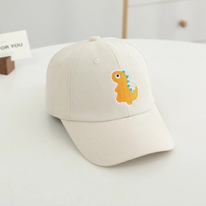 Détail de la broderie dinosaure orange sur une casquette en coton crème pour enfant