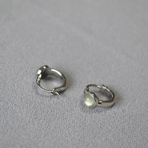 Close-up of vintage brass earrings with inlaid pale green agate stones on fabric