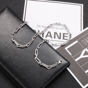Silver stainless steel paperclip link chain necklace with lobster clasp on a black surface