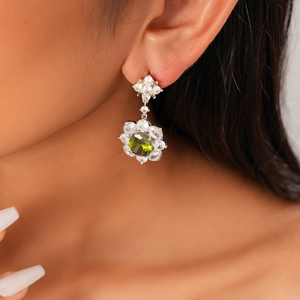Close-up of olive green zircon flower earrings on model highlighting retro vintage style