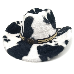 Macro detail of the cow print plush texture and bronze bull head metal badge on cowboy hat