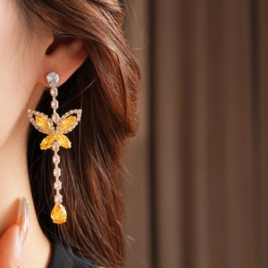 Close-up of golden butterfly drop earrings with yellow zircon crystals on model