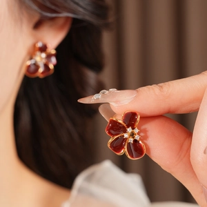 Close-up of vintage flower earrings with dark red enamel petals and zircon centers