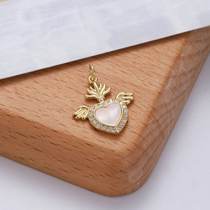Ciondolo cuore con ali dorato con intarsio rosa e corona su superficie di legno