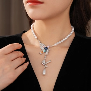 Détail du collier vintage oiseau avec pierres colorées et perle en goutte sur le mannequin