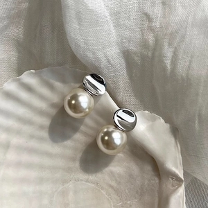 Detailed shot of elegant pearl earrings on shell tray with minimalist aesthetic