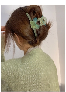 Detail of gradient green butterfly hair claw clip worn on a woman's hair for a sweet style