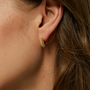 Golden croissant hoop earrings featuring a vintage textured metal finish on a model