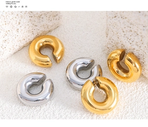 Detailed view of polished gold and silver thick C-shape ear cuffs on white textured stones