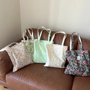 Detailed view of five floral and textured cotton tote bags on a vintage brown leather sofa