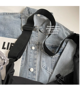 Detail shot of the adjustable wide nylon shoulder strap on a black crossbody bag
